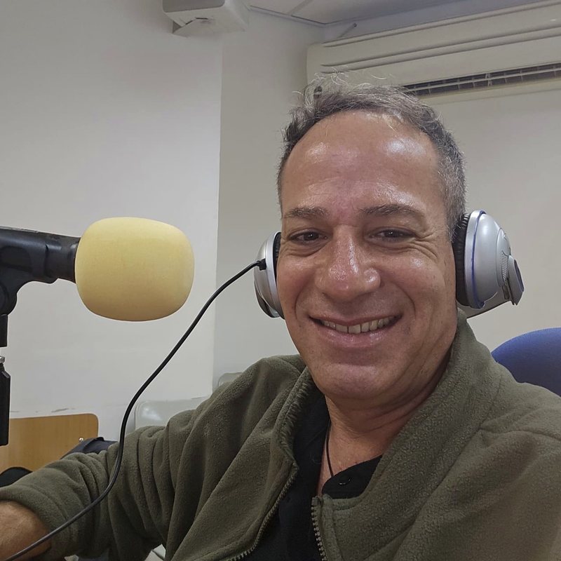 אלון שמש מקליט פרק פודקאסט באולפן, עם אוזניות מול המיקרופון